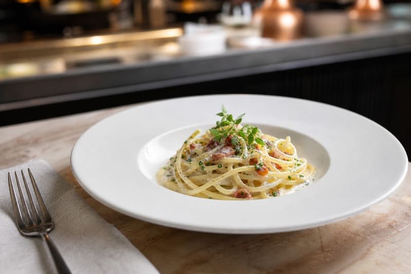 Pasta plated in a white wide-rim melamine bowl with clean rim space